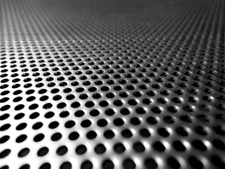 Holes of grey metal plate with round regular holes texture background.